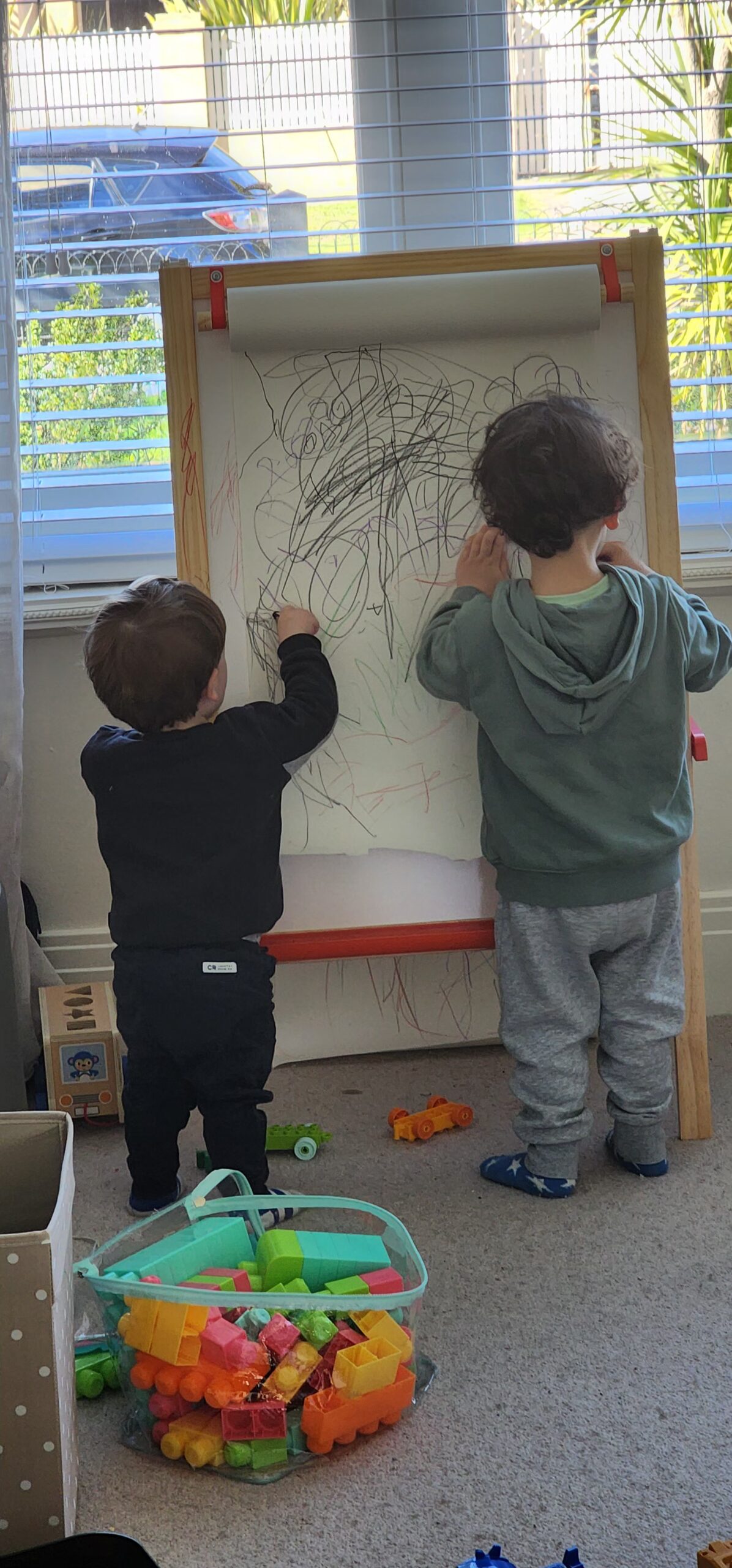 Two boys drawing on an easel